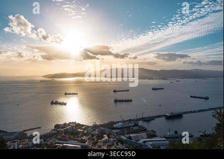 Una vista panoramica del porto di Gibilterra al tramonto, con numerose navi da carico e navi ancorate nella baia. Il paesaggio urbano e l'infrastruttura portuale Foto Stock