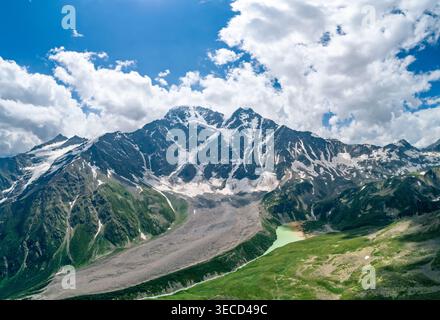 Il paesaggio montano mostra vette spettacolari e valli lussureggianti sotto un cielo blu vibrante Foto Stock