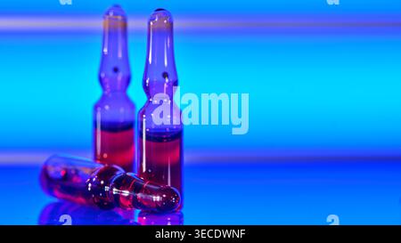 Fiale mediche con liquido rosso su sfondo blu al neon Foto Stock