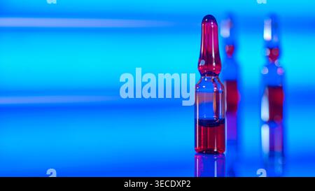 Fiale mediche con liquido rosso su sfondo blu al neon Foto Stock