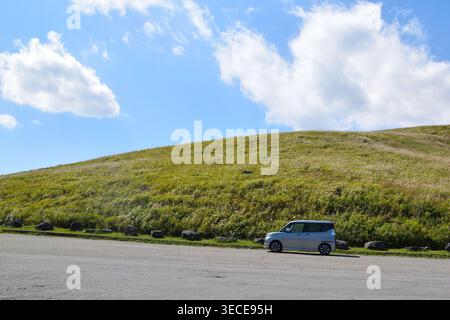 Carrozza Silver in salita sulla linea Venus a Nagano, Giappone, con colline verdi e cielo blu Foto Stock