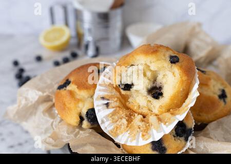 Composizione accurata dei muffin ai mirtilli con uova limone e elementi da forno su una superficie leggera Foto Stock