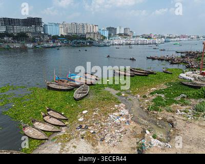Vista aerea del fiume Buriganga con barche in legno ormeggiate vicino alla riva e lo skyline della città a Dacca, Divisione di Dacca, Bangladesh. Foto Stock