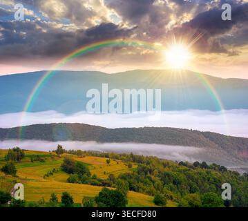 tramonto sull'area rurale montagnosa in primavera. paesaggio montano remoto con dolci colline boscose. splendido luogo nebbioso di campagna alpina Foto Stock