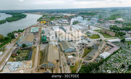 Vista aerea di un complesso industriale con grandi magazzini e camini fumanti vicino al fiume Sava a Sabac, Vojvodina, Serbia. Foto Stock