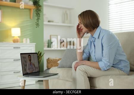 Telemedicina. Donna che ha consulto online con il medico via portatile a casa Foto Stock