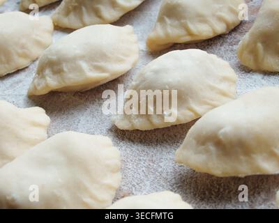 cucinare. Gnocchi con formaggio fresco. Preparazione di gnocchi su una tavola di legno. Gnocchi crudi con ripieno di formaggio preparati per la cottura su un bo di legno Foto Stock