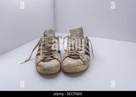 Un paio di vecchie sneakers usate, su sfondo bianco, scarpe sportive sporche con lacci sporchi Foto Stock