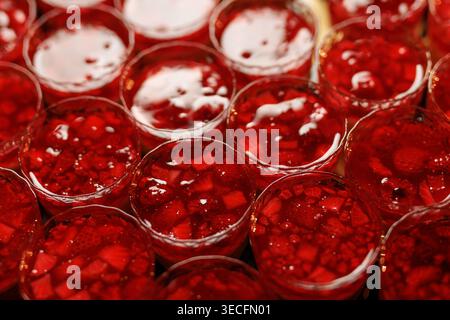Porzioni singole di gelatina rossa traslucida, confezionate con fragole e lamponi freschi. Foto Stock
