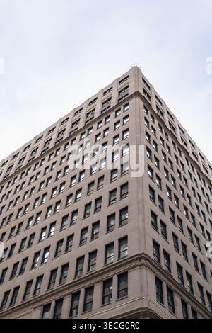 Un alto edificio a Chicago mostra i suoi dettagli d'angolo contro un cielo nuvoloso. La struttura presenta molte finestre e appare vuota. Nessuna attività è visibile in Foto Stock