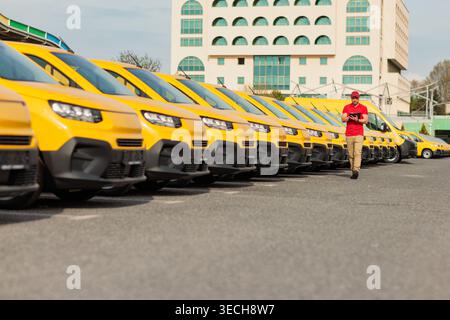 Furgoni gialli in un parcheggio con un corriere Foto Stock