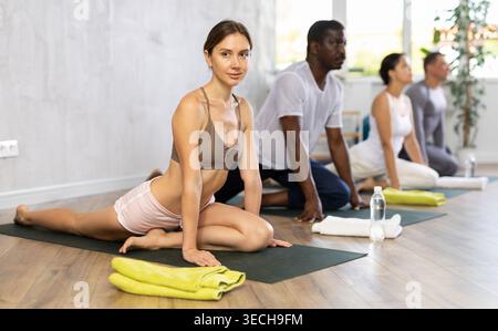 Giovane donna che fa cobra posa per la salute e il benessere con il gruppo insieme presso lo studio di yoga Foto Stock