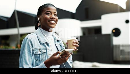 Caffè, camminata e donna nera in città con auricolari per musica, pensiero e spostamenti mattutini. Persona felice, in viaggio e d'affari con cellulare per Foto Stock