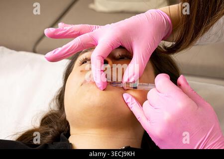 Una foto di una giovane donna molto bella e attraente che mostra l'iniezione delle labbra e il processo di ringiovanimento, in un ufficio progettato professionalmente. Questo Foto Stock