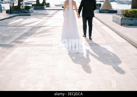 La sposa e lo sposo si allontanano. Il percorso illuminato dal sole testimonia la loro ritirata Foto Stock