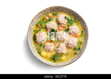 Abbondante zuppa di polpette in un recipiente isolato su sfondo bianco, vista dall'alto, elemento di design. Zuppa di polpette di pollo fatta in casa con verdure e verdure primaverili. Foto Stock