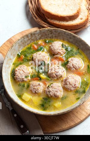 Abbondante zuppa di polpette in ciotola guarnita con verdure ed erbe verdi. Zuppa di polpette di pollo fatta in casa con verdure primaverili. Foto Stock