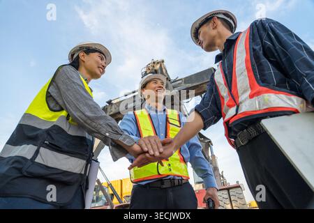 Diversi operatori marittimi asiatici di medie dimensioni si accatastano in una dimostrazione di collaborazione e unità in un cantiere logistico tailandese per la cooperazione commerciale e il lavoro Foto Stock