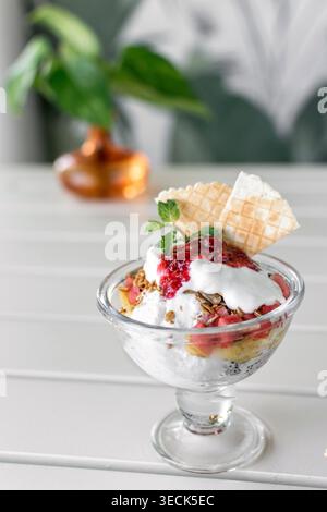 gelato e dessert misti di frutta in tazza di vetro sul tavolo bianco all'aperto di giorno Foto Stock