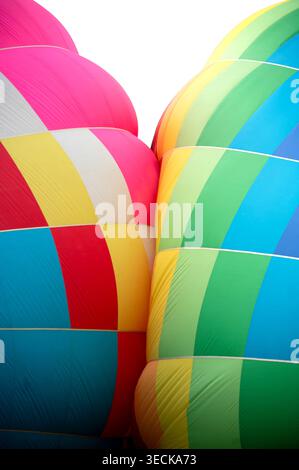 Primo piano di due colorate buste di palloncino ad aria calda affiancate, che mostrano pannelli in tessuto a righe luminose e forme curve, catturando l'energia del fligh Foto Stock