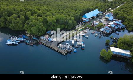 Vista aerea: Mercato del pesce e porto delle isole Mentawai, Indonesia. Barche locali, palafitte e mangrovie alla luce del pomeriggio. Girato tramite DJI Mavic Air 3S.. Foto Stock