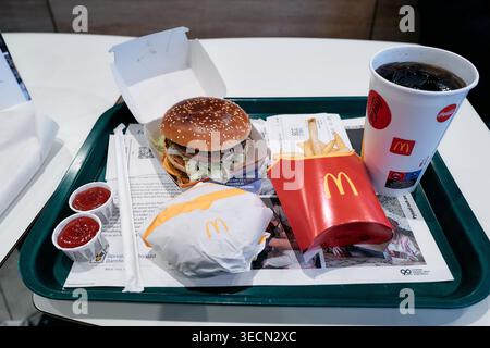 Big mac si siede su un vassoio, pronto a mangiare. Hamburger, patatine fritte e bevande riposano su un vassoio di plastica verde Le tazze rosse e i contenitori per salsa aggiungono colori vivaci. Nynashamn, Foto Stock