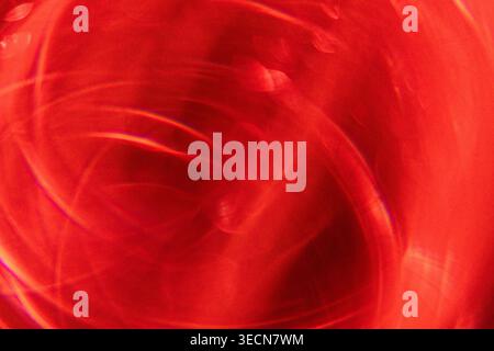 Immagine astratta con un motivo rosso vorticoso con riflessi di luce, che crea un effetto visivo dinamico e vibrante per i progetti creativi Foto Stock