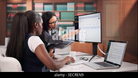 Gli avvocati esaminano attentamente i documenti contrattuali su laptop in Office Meeting. Foto Stock