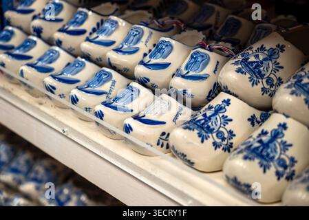 File di zoccoli in porcellana Delft Blue tradizionali con design classico di mulino a vento e tulipani su uno scaffale del negozio di articoli da regalo. Foto Stock