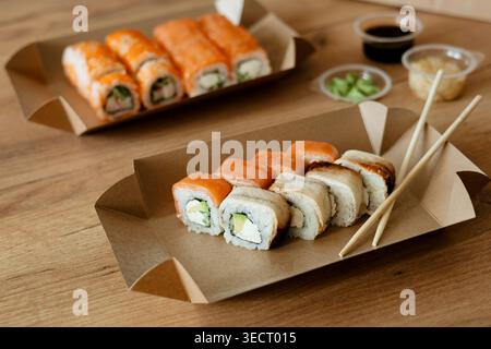 Una giornata rilassante a casa con un delizioso sushi presentato in confezioni ecologiche, con una varietà di rotoli freschi e colorati, perfetti per un indu Foto Stock