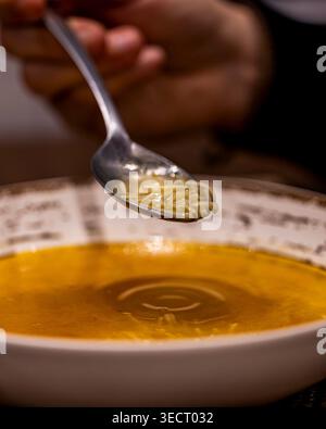Primo piano di un'abbondante zuppa di cocido tradizionale spagnola, con ricco brodo con delicati spaghetti. Un classico cibo confortevole e un punto di riferimento in spagnolo Foto Stock