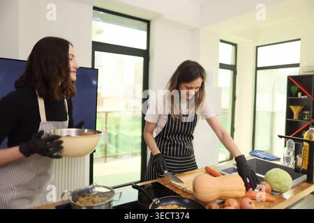 Cucinare insieme agli amici in una cucina luminosa, assaporare l'arte di preparare pasti deliziosi e condividere momenti di gioia Foto Stock