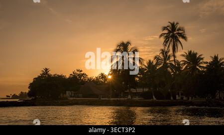Tramonto dorato sul Mar dei Caraibi in Costa Rica, con palme sagomate e una costa tranquilla, riflessi d'acqua calmi e caldi eveni tropicali Foto Stock