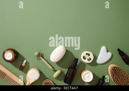 Una selezione di cosmetici e prodotti per la cura della pelle ecologici su uno sfondo verde. Con creme organiche, oli, rullo di giada e accessori sostenibili Foto Stock