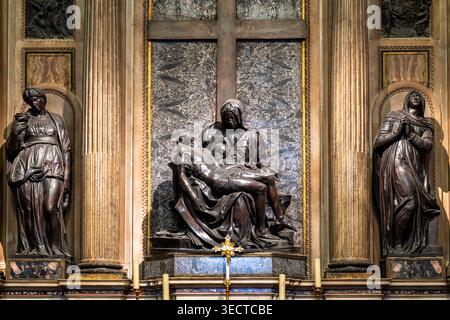 Statue in bronzo di donne e Vergine Maria che trasportano Gesù morto in piedi davanti alle mura decorate con motivi cristiani all'interno della storica chiesa di Roma Foto Stock