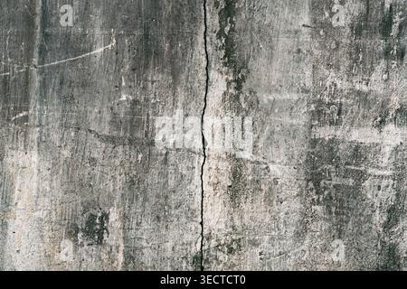 Calcestruzzo verniciato sbucciato in stile grunge urbano superficie unica e morbida della parete con fori, graffi sporchi e una grossa spaccatura verticale Foto Stock