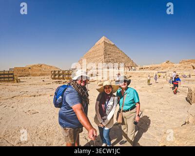 GIZA, IL CAIRO, EGITTO - 24 MAGGIO 2025: Tre turisti si mettono in posa per un selfie di fronte alla Piramide di Khafre presso il complesso delle grandi Piramidi di Giza, con la S Foto Stock