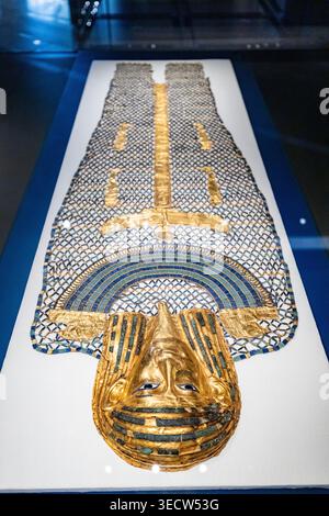 GRAND EGYPTIAN MUSEUM, CAIRO, EGITTO - 25 MAGGIO 2025: Un'antica copertura di rete con perline di mummia egiziana con una maschera dorata, decorata con perline di faience e. Foto Stock