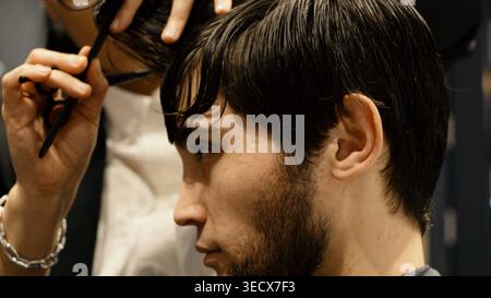 Profilo di un uomo che si fa tagliare i capelli in un barbiere Foto Stock