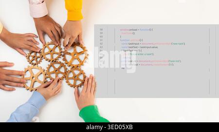 Un primo piano di mani diverse che lavorano insieme a ingranaggi in legno ed elementi di codifica, mostrando collaborazione e innovazione in un'azienda o. Foto Stock