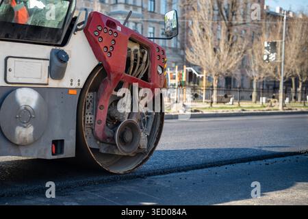 Rullo per la posa di asfalto caldo fresco sulla strada, strada cittadina. Attrezzature per la costruzione di strade. Foto Stock