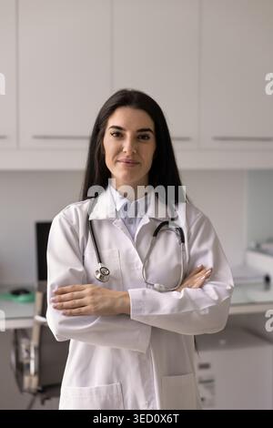 Donna ispanica medico si trova con fiducia nel moderno studio medico Foto Stock