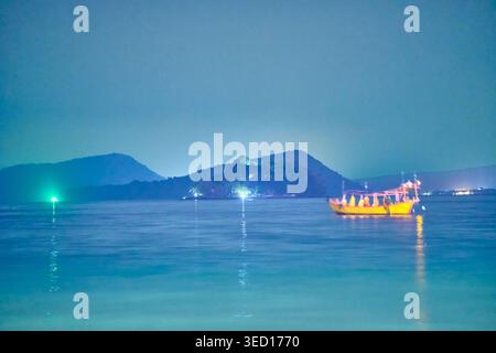 Panorama notturno della costa di Koh Rong con molo illuminato e piccola barca con luci verdi rosse. Foto di alta qualità Foto Stock