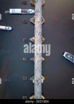 Vista aerea dall'alto verso il basso del Ponte Carlo di Praga, con persone a piedi e barche in tour panoramico Foto Stock