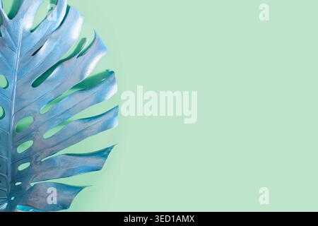 Tropical dipinta di foglie di palma Monstera sul neo color menta. Configurazione astratta per la progettazione e lo spazio per il testo. Foto Stock