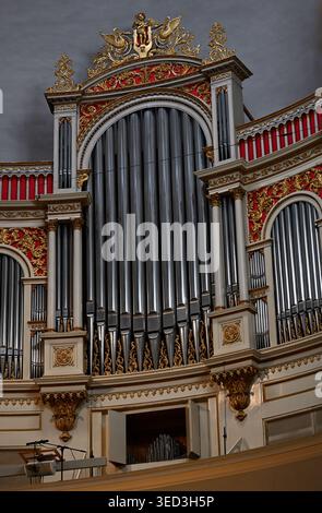 Organo a canne decorato con decorazioni dorate e accenti rossi all'interno di una chiesa storica, che mostra intricate lavorazioni artigianali e classici des architettonici Foto Stock