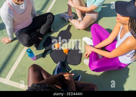 Amici che riposano su un campo da baseball dopo la partita Foto Stock