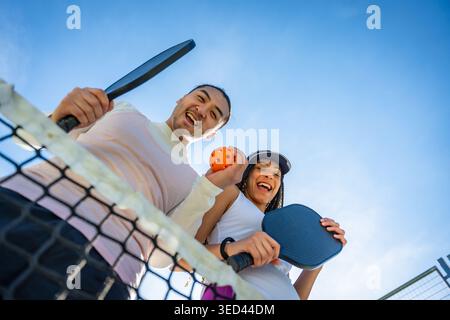 Coppia allegra e variegata che gioca a Pickleball sul campo all'aperto Foto Stock