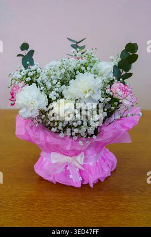 Fiori in una confezione rosa su un tavolo di legno Foto Stock