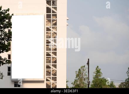Grande cartellone bianco montato su una facciata moderna di un edificio accanto a una scala esterna, che fornisce spazio libero per la pubblicità all'aperto, il branding, Foto Stock